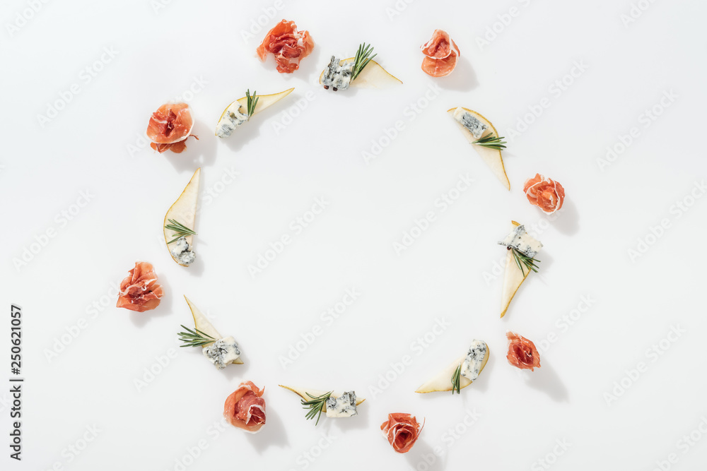 top view of sliced pears with blue cheese and rosemary twigs near tasty prosciutto on white background