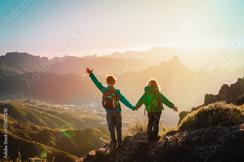 Photography happy boy and girl travel in mountains at sunset, kids enjoy hiking