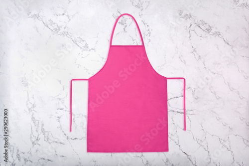 Pink kitchen apron on white marble texture with natural pattern. Blank apron on marble background. Flat lay