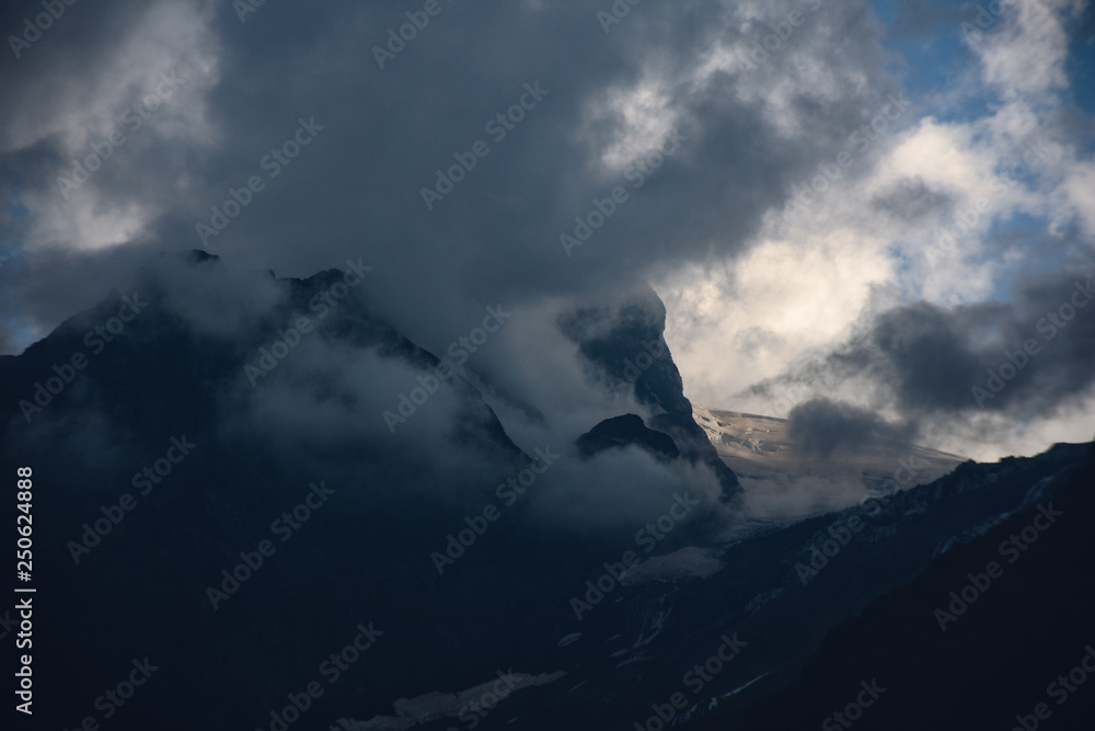 Peaks of Dombai mountains in summer rain clouds Peaks of Dombai mountains in summer rain clouds