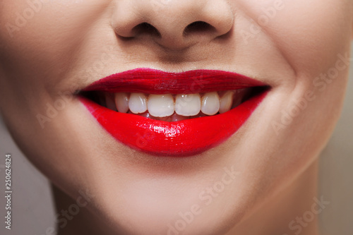 Beautiful women's lips with bright red lipstick and white teeth.