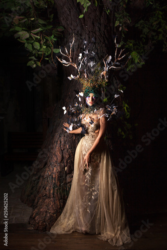 natural nymph with horns like branches of a tree and butterflies circling around. Fantasy style costume photo