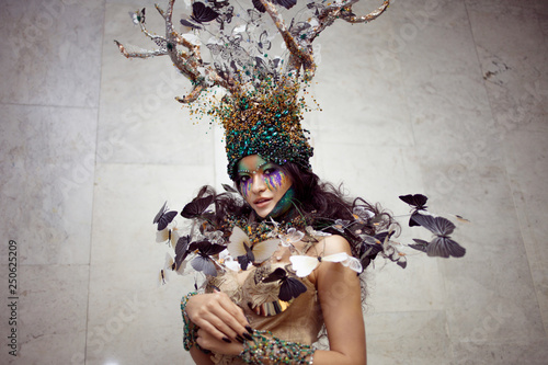 natural nymph with horns like branches of a tree and butterflies circling around. Fantasy style costume photo