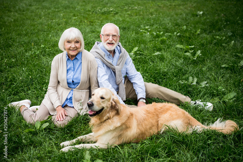 happy senior couple with adorable golden retriever dog sitting on green lawn © LIGHTFIELD STUDIOS