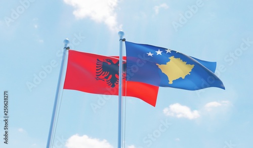 Kosovo and Albania, two flags waving against blue sky. 3d image
