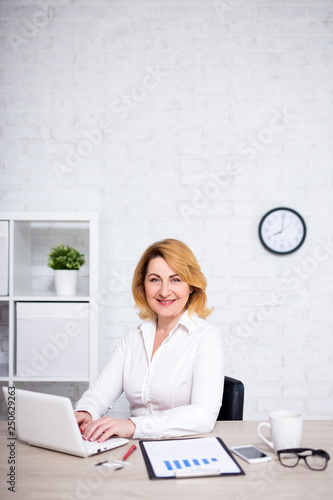 portrait of mature business woman working in office and copy space over white wall
