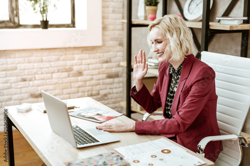 Fotografie Beaming blonde businesswoman waving her hand during parting