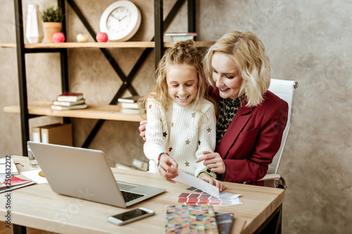 Cheerful cute little child inspecting colored samples with her hands photo