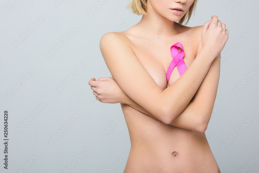 cropped view of naked girl with pink breast cancer awareness ribbon, isolated on grey cropped view of naked girl with pink breast cancer awareness ribbon, isolated on grey
