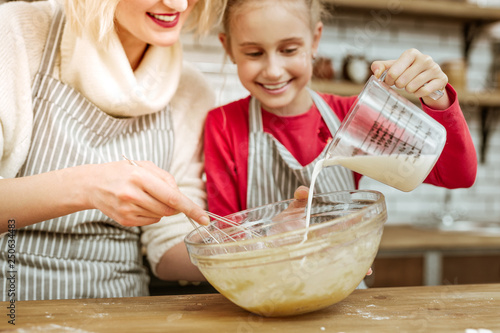 Valokuva Happy joyful little kid adding milk from measuring cup