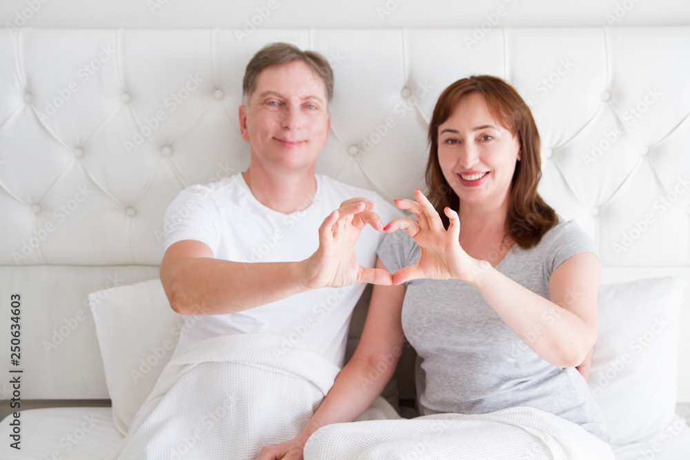 Middle aged senior couple in bed. Family happy relationship man and woman at bedroom interior. Sexual health and menopause period concept. Selective focus Middle aged senior couple in bed. Family happy relationship man and woman at bedroom interior. Sexual health and menopause period concept. Selective focus