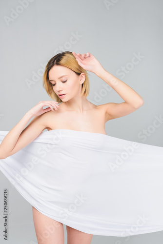 blonde naked girl posing in elegant white cloth, isolated on grey