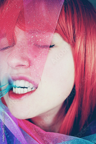 Artistic portrait of a young redhead woman covering by a glitter chiffon
