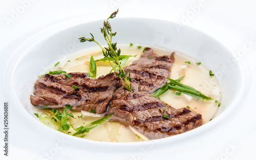 Broth with fried veal on white background