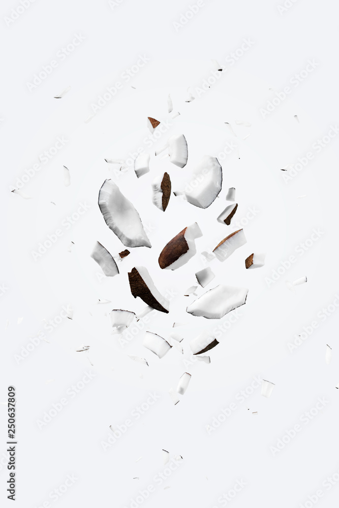 Flying pieces of coconut on white color. Exotic levitation concept for cosmetics, spa, perfume, health care products, aroma background with copy space - obrazy, fototapety, plakaty 