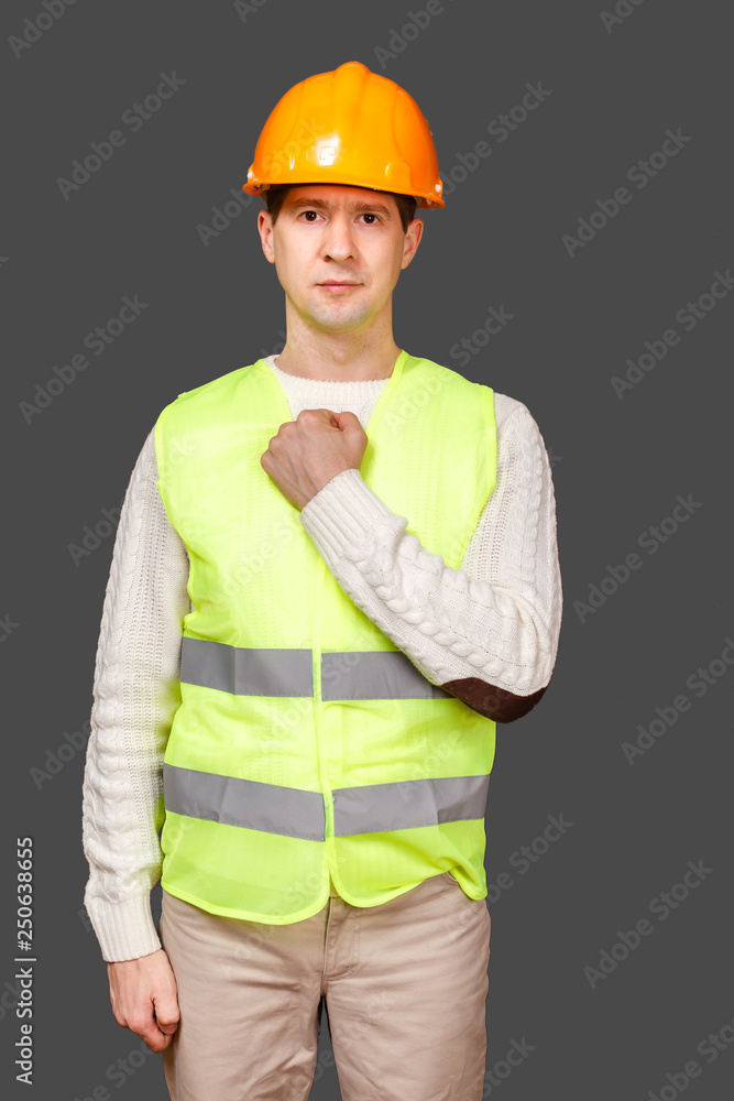The man the builder in a helmet and a vest beats breast a fist