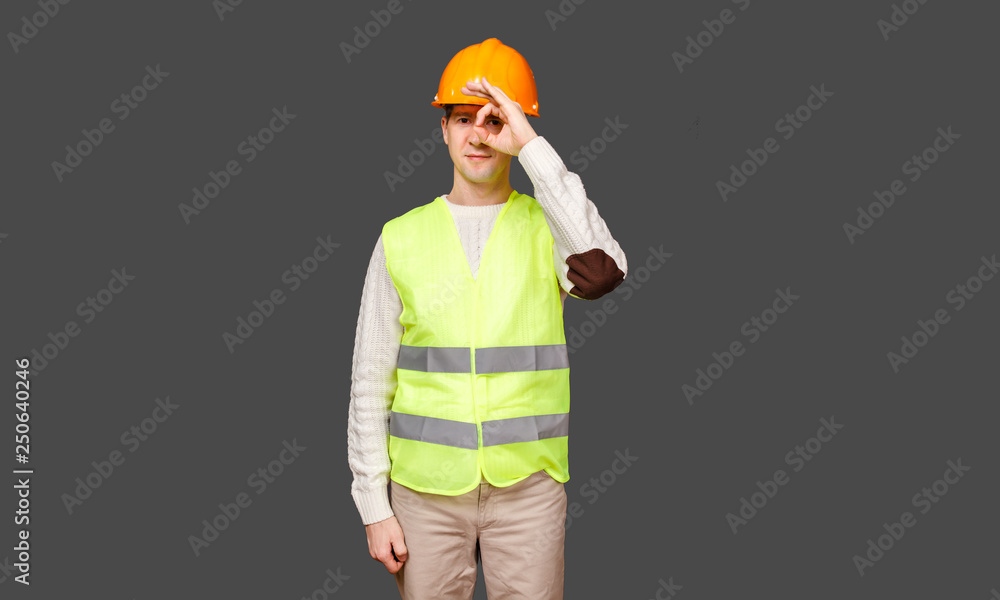 The man the builder in a helmet and a vest, gesture - OK, everything is good The man the builder in a helmet and a vest, gesture - OK, everything is good