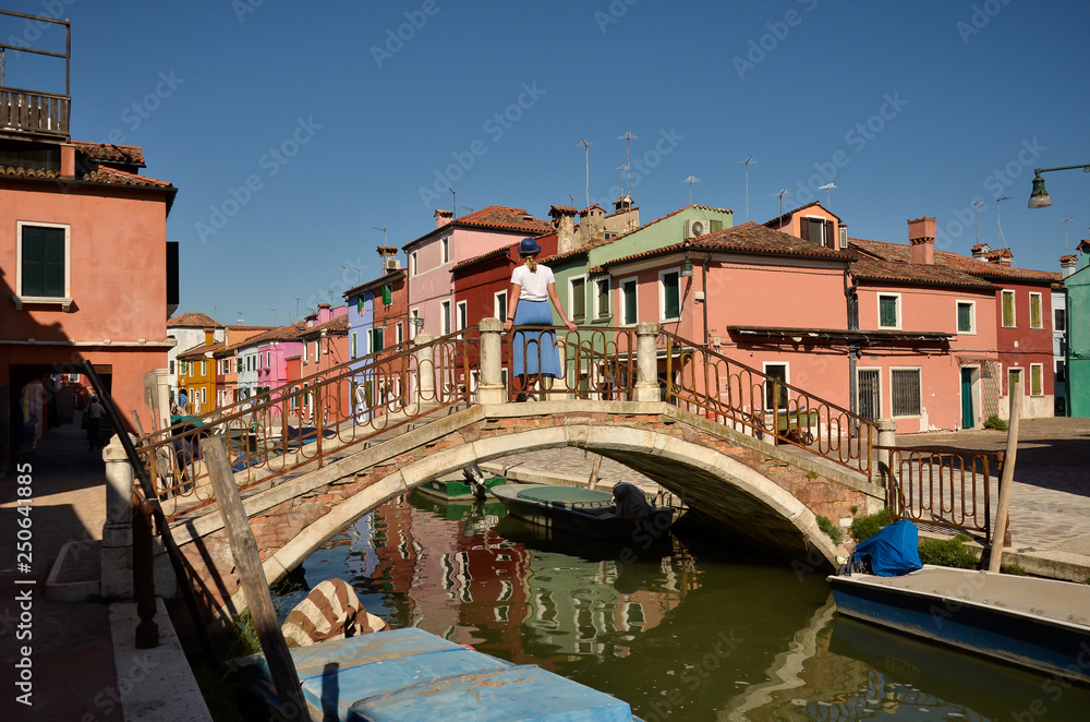 Venice, Burano island canal, small colored houses and the boats. Woman tourist. Colorful concept.