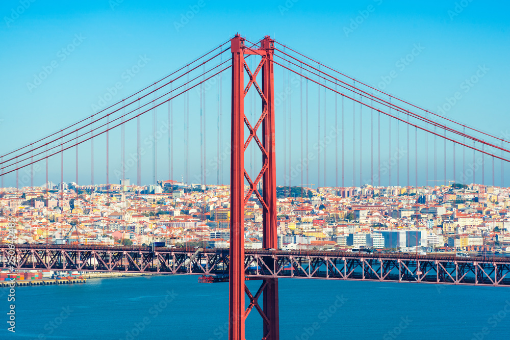 Lisbon, Portugal: The Bridge of 25th April with car traffic and panoramic view of the city on the background. Bridge structure up close