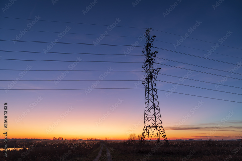 Fototapeta premium Silhouette of electrical tower during a beautiful dusk in the Dutch countryside.