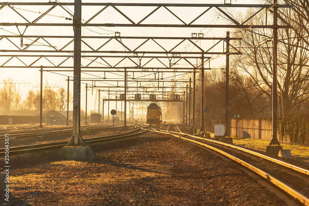 A train and railroad tracks during a colourful sunrise. Groningen, Holland. A train and railroad tracks during a colourful sunrise. Groningen, Holland.