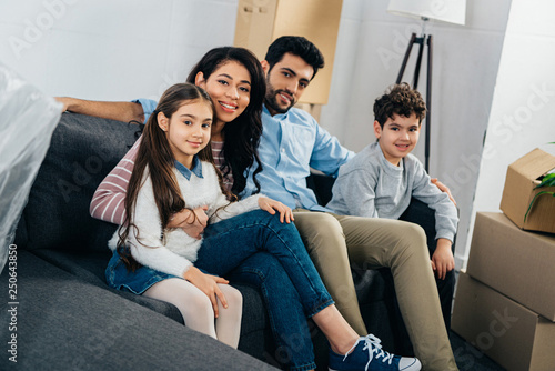 happy hispanic family sitting on sofa in new home