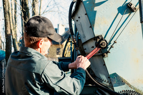 Farmer mechanic repairing agricultural potato harvester. Male hand holding wrench, repairing combine harvester.