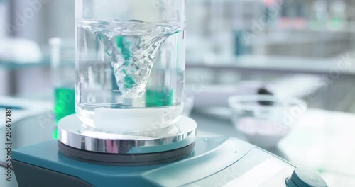 Swirling vortex of water in beaker with laboratory in background