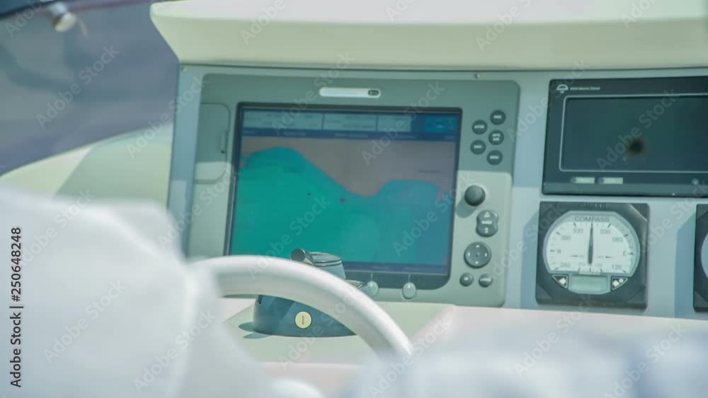 The yacht's captain is navigating a steering wheel. We can also see a screen. The yacht's captain is navigating a steering wheel. We can also see a screen.