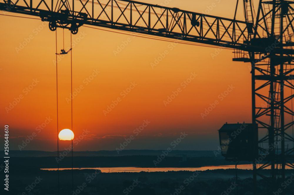 Silhouette of a construction crane on the background of the setting sun. Silhouette of a construction crane on the background of the setting sun.