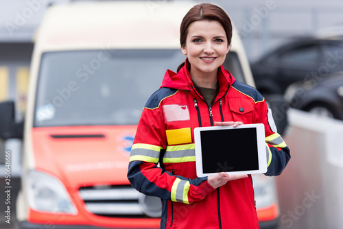 Smiling paramedic in red uniform holding digital tablet with blank screen photo