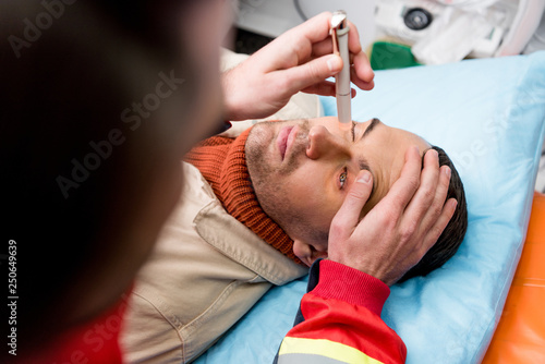Cropped view of paramedic doing eye examining with patient