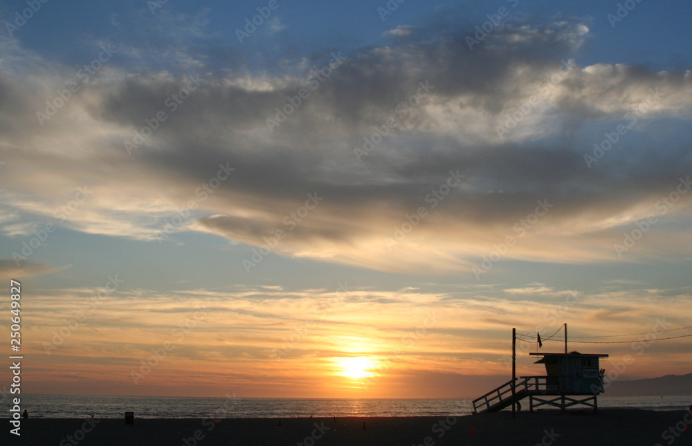 Silouetted lifeguard station against a dramatic sunset sky