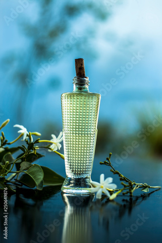 Close up of spray or perfume of Indian jasmine flower or juhi or Jasminum Auriculatum on wooden surface in a small bottle with raw flowers. photo