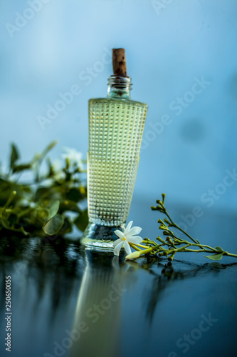 Close up of spray or perfume of Indian jasmine flower or juhi or Jasminum Auriculatum on wooden surface in a small bottle with raw flowers. photo