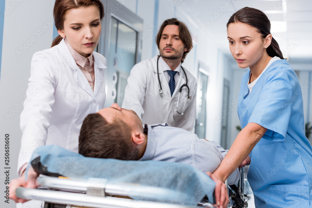Fototapeta premium Doctors and nurse transporting unconscious patient on gurney