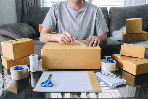 Young entrepreneur SME man receive order client and working with packaging sort box delivery online market on purchase order and preparing package product, Small business parcel for shipment