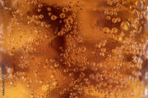 Sparkling bubbles of cola and ice cubes close up.