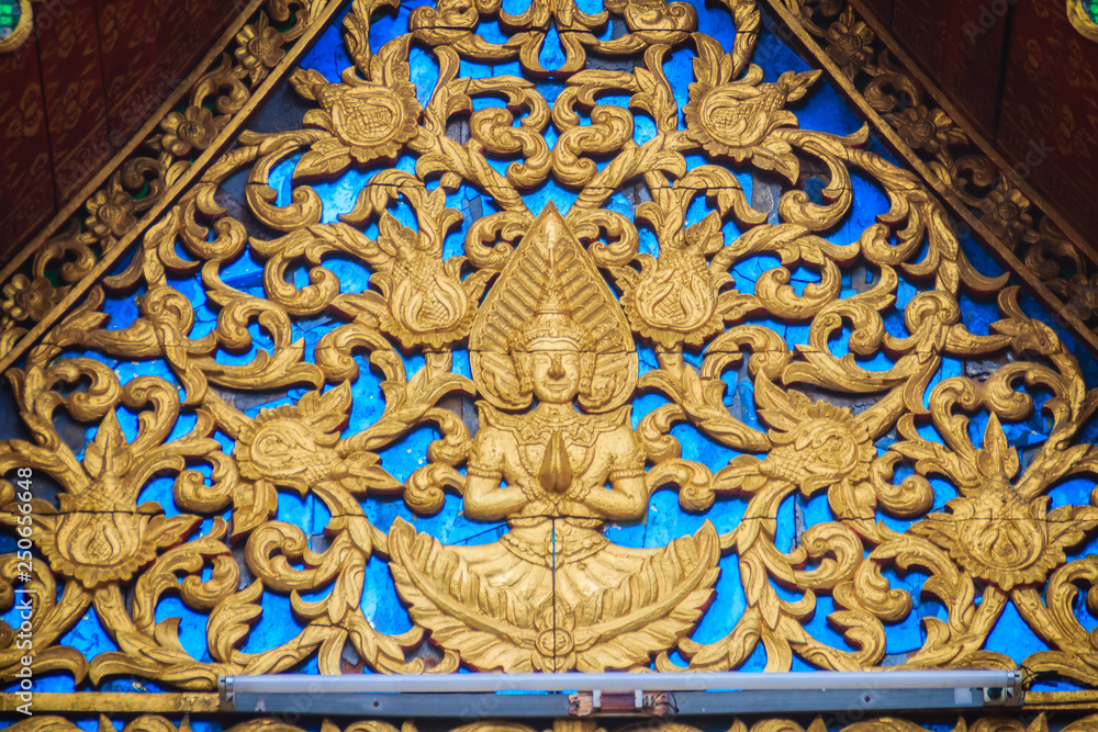 Beautiful golden gable chapel with engraved angel sculpture. An angel sculpture was decorated on the gable top at the temple in Thailand.