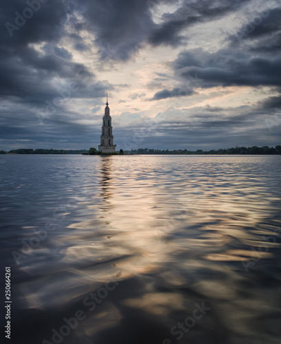 View of flooded bell tower of St. Nicholas Cathedral in Kalyazin on Volga River. Russian landscape with bell tower, stones in foreground, beautiful sky