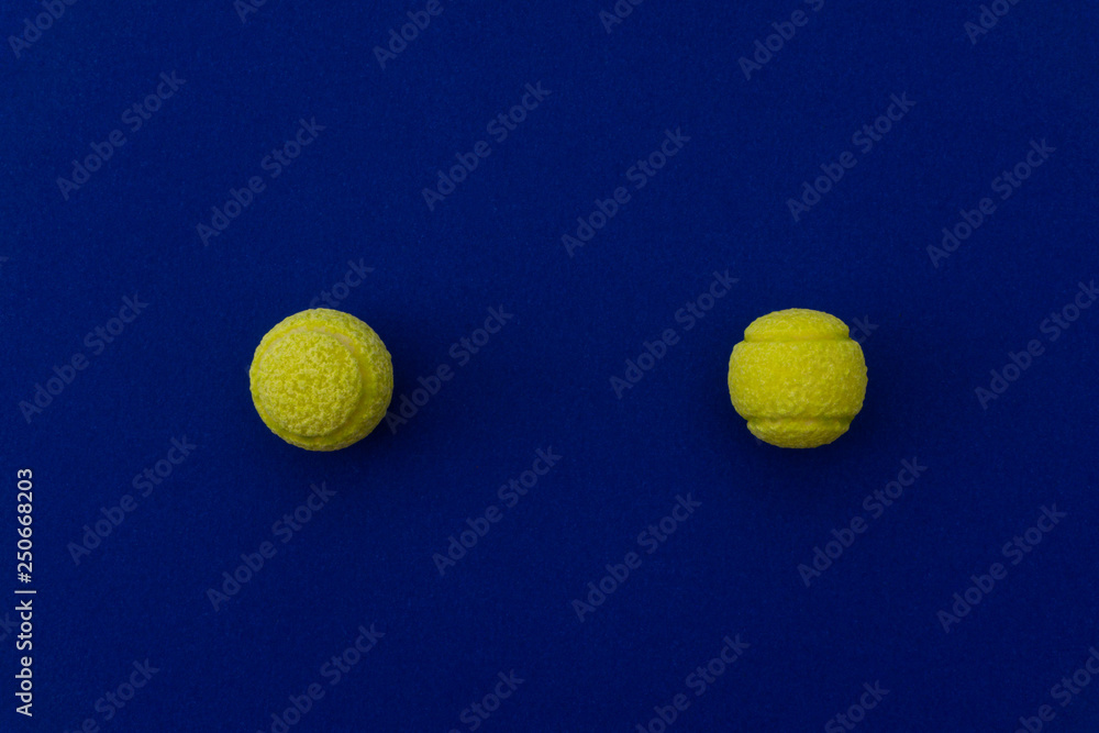 Two tennis balls composition on blue background. Top view.