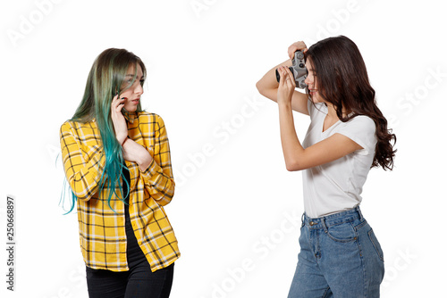 Young woman taking a picture of pretty girl, white background