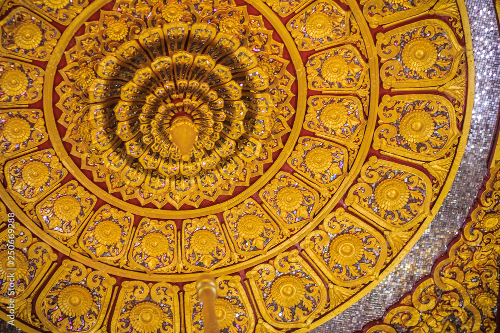 Beautiful golden decorated ceiling in lotus shape with lamp at the Buddhist church, Thailand.