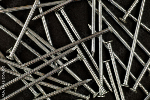 Background. A structure consisting of new shiny nails on a dark background.