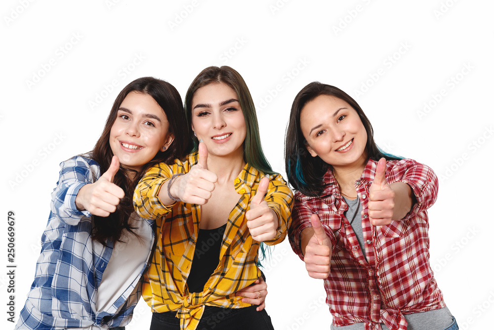 Portrait of three beautiful young happy females smiling joyfully showing thumbs up isolated on white Portrait of three beautiful young happy females smiling joyfully showing thumbs up isolated on white