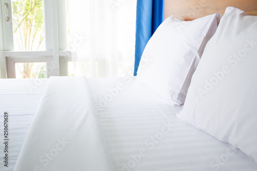 White towels on bed in hotel with garden view in background. © DG PhotoStock