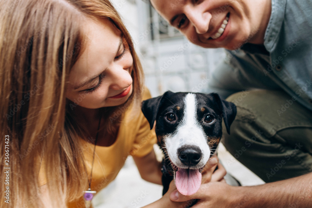 Young cute couple in love playing with dog puppy jack russell with tongue Young cute couple in love playing with dog puppy jack russell with tongue