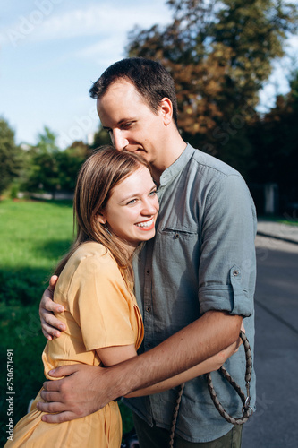 Beautiful young couple in casual clothes hugging and smiling outside on summer hot day