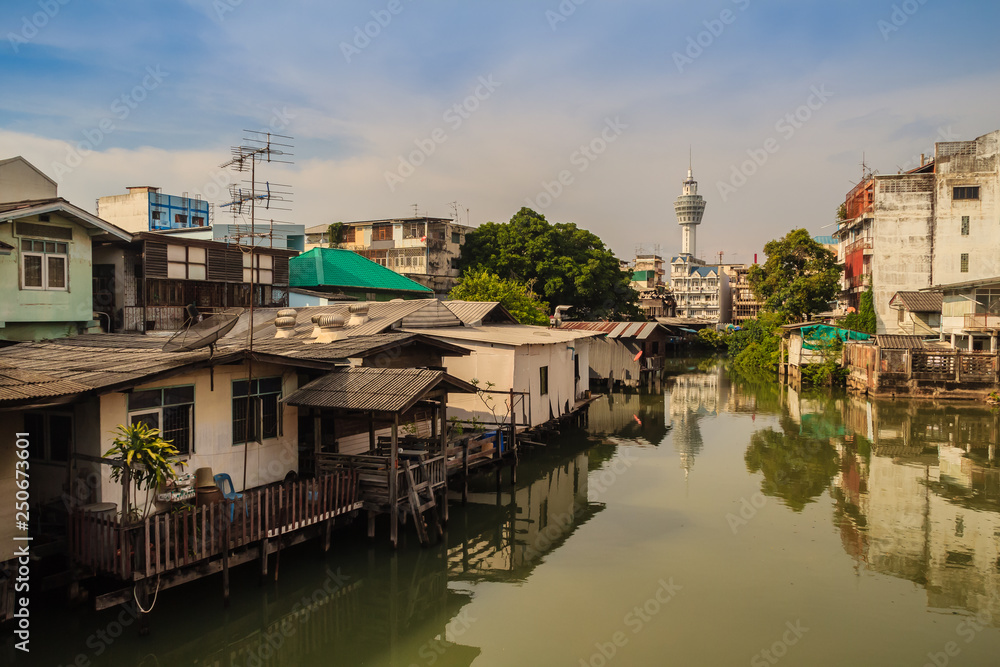 Obraz premium Samut Prakarn observation tower with canal and village in foreground and blue sky background. Samut Prakan is located at the mouth of the Chao Phraya River on Gulf of Thailand.