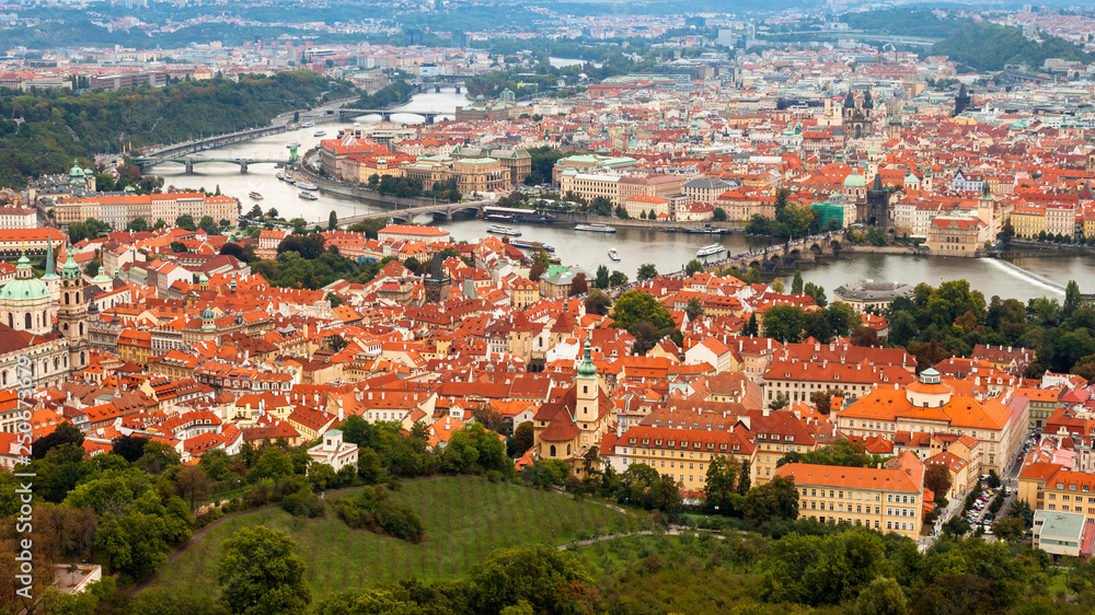 Aerial shot of Prague, Czech Republic capital, with Vltava river, many bridges and houses with orange roofs.